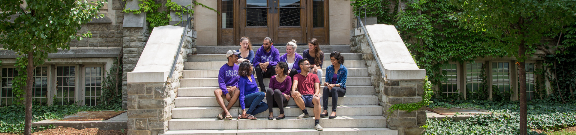 Several students sit together using laptops in a large room.