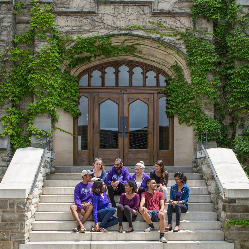 Several students sit together using laptops in a large room.
